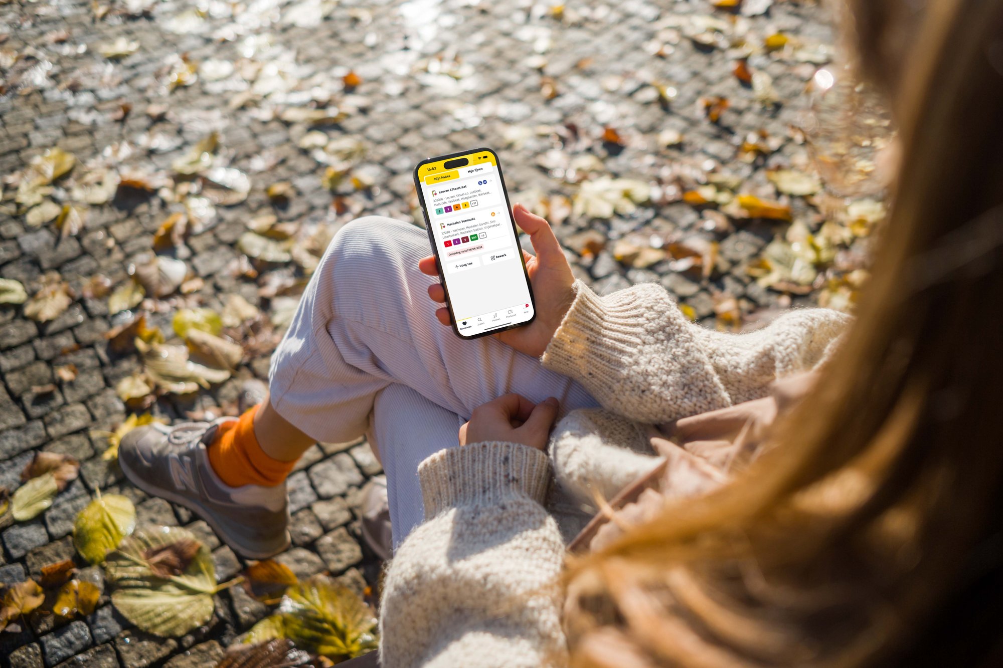 woman holding mobile phone with De Lijn app